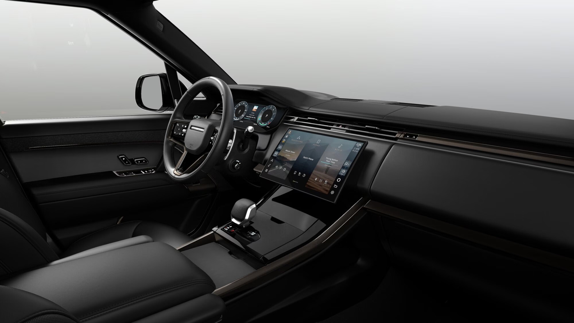 Interior de um carro moderno com acabamento em tons escuros. Volante multifuncional à esquerda, painel digital e uma tela multimídia central exibindo um menu com ícones de aplicativos. O console central possui um seletor de marchas e botões de controle. Os bancos são de couro preto, e a porta do motorista tem controles de vidro e espelho. O ambiente é sofisticado e tecnológico