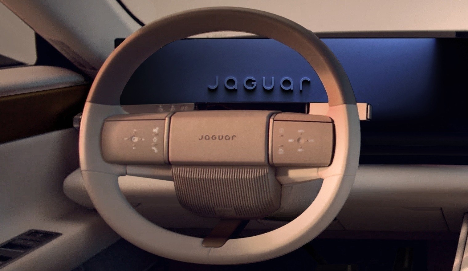 Interior de um carro moderno, com volante bege claro e painel digital escuro exibindo o nome Jaguar em relevo. O volante possui botões de controle e o nome Jaguar gravado no centro, com detalhes canelados na parte inferior. A iluminação suave destaca o design futurista do veículo