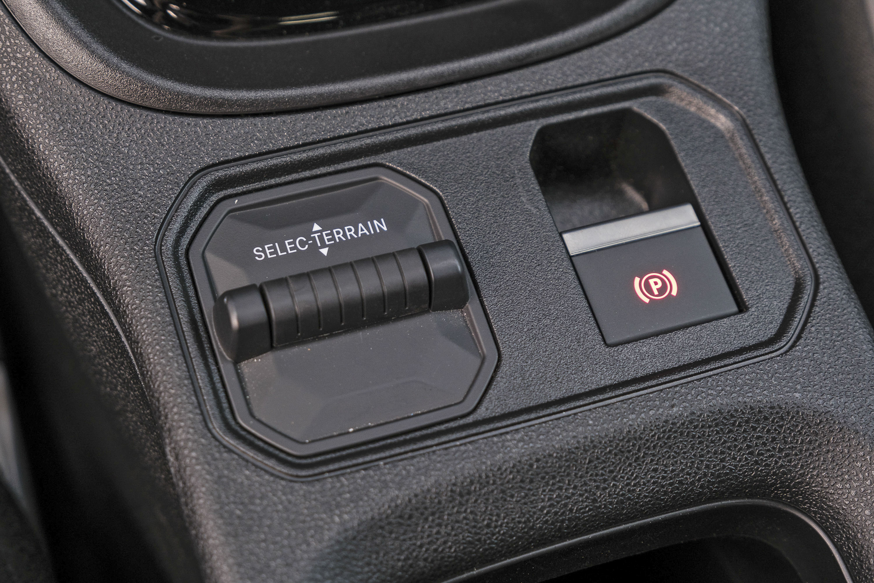 Painel de controle automotivo com seletor de terreno SELEC-TERRAIN e botão do freio de estacionamento eletrônico aceso em vermelho