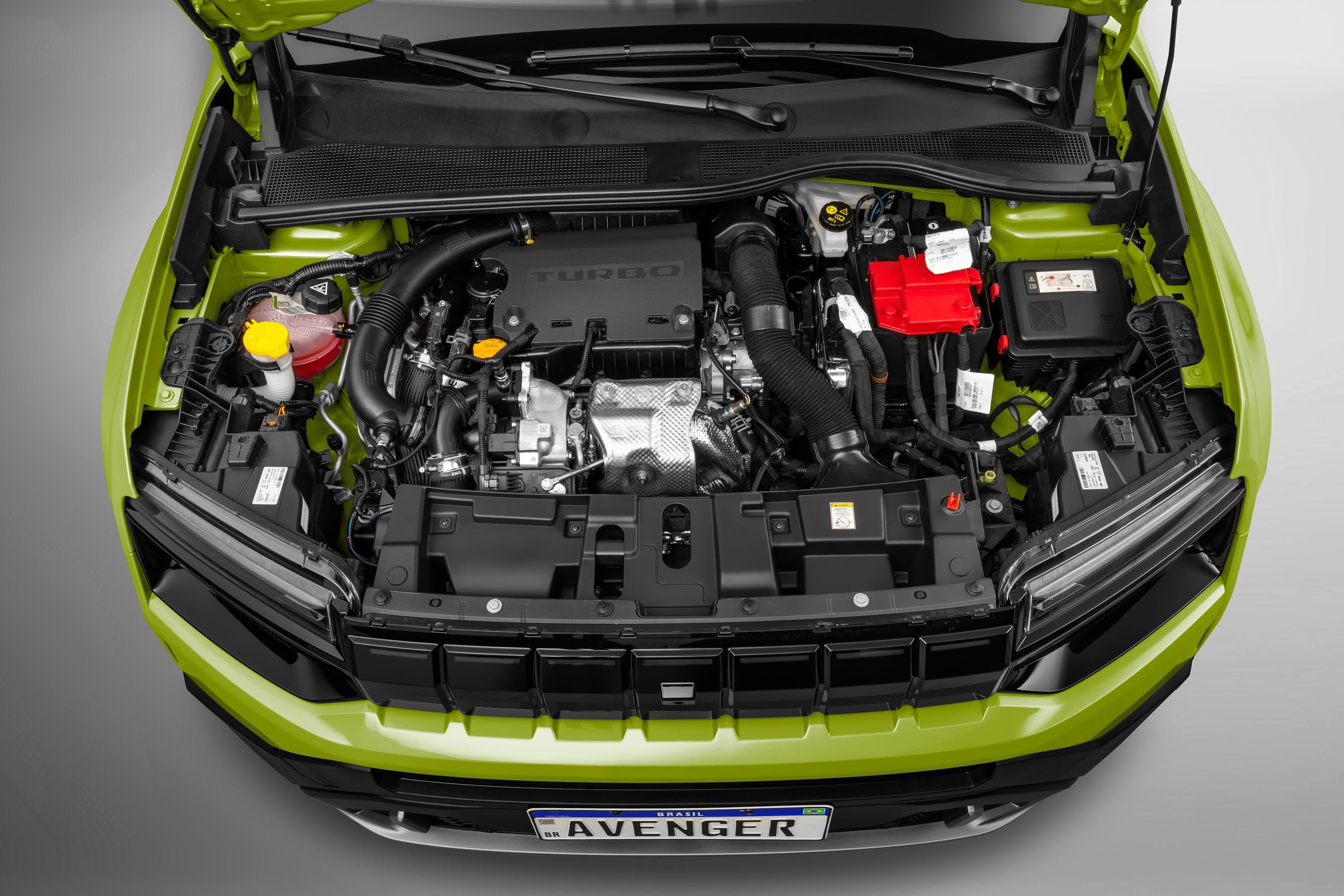 Motor de um carro verde-limão visto de cima, com o capô aberto. Componentes como o motor turbo, bateria vermelha e reservatórios de fluidos são visíveis, com a grade frontal preta e a placa AVENGER na parte inferior