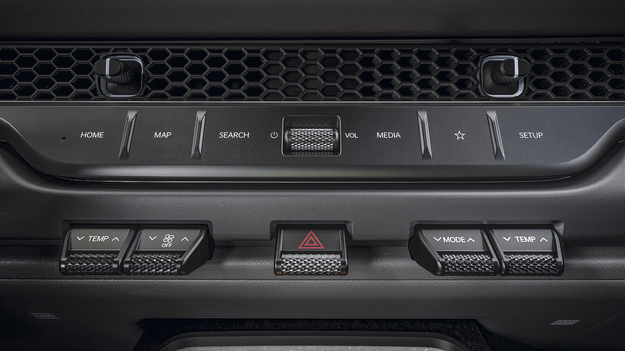 Painel de controle automotivo escuro com botões para HOME, MAP, SEARCH, VOL, MEDIA e SETUP. Abaixo, controles de temperatura e modo, e um botão de alerta triangular vermelho no centro