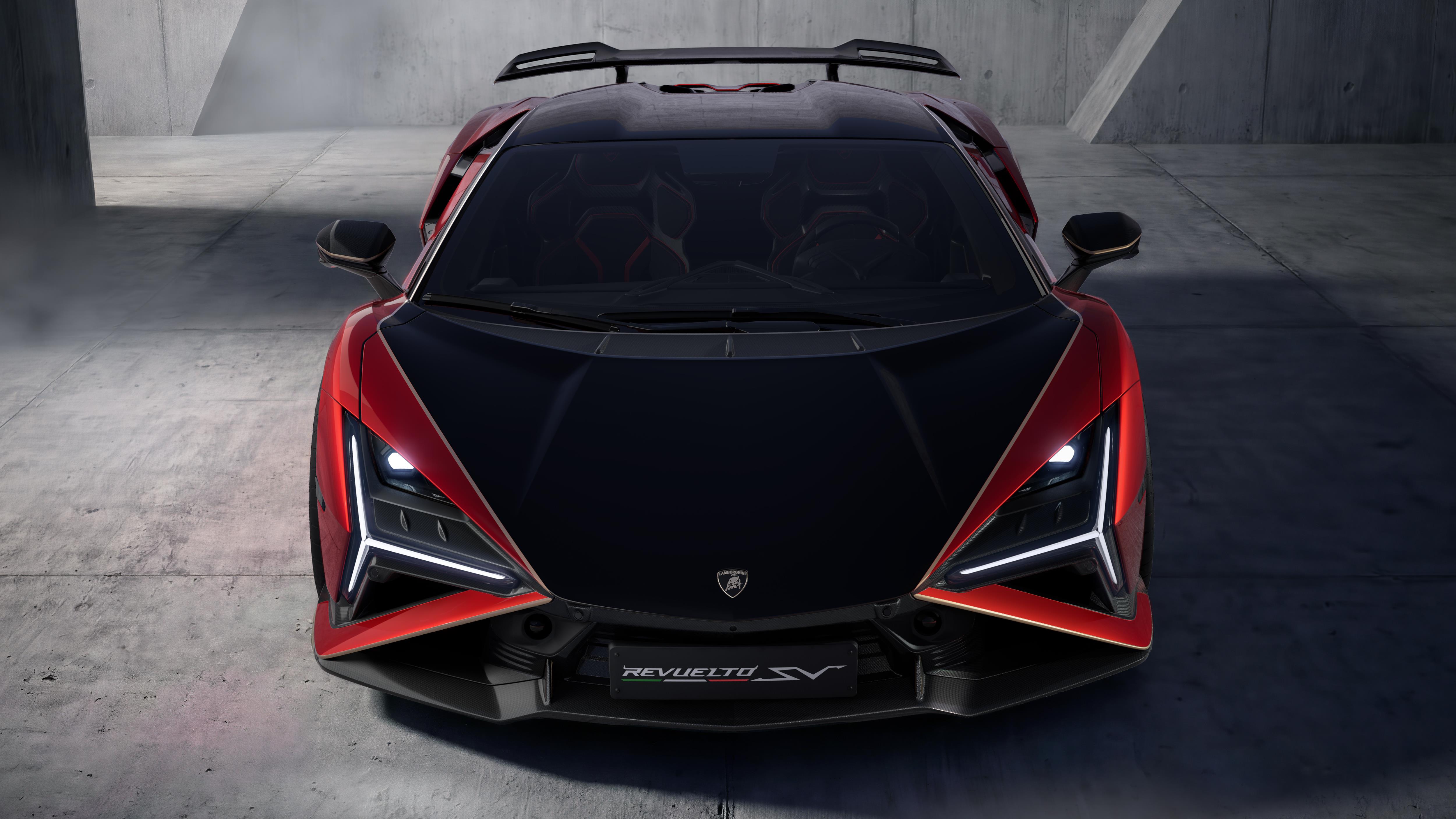 Carro esportivo Lamborghini Revuelto SV preto e vermelho, visto de frente, com faróis acesos em formato de Y, sobre piso de concreto em ambiente escuro