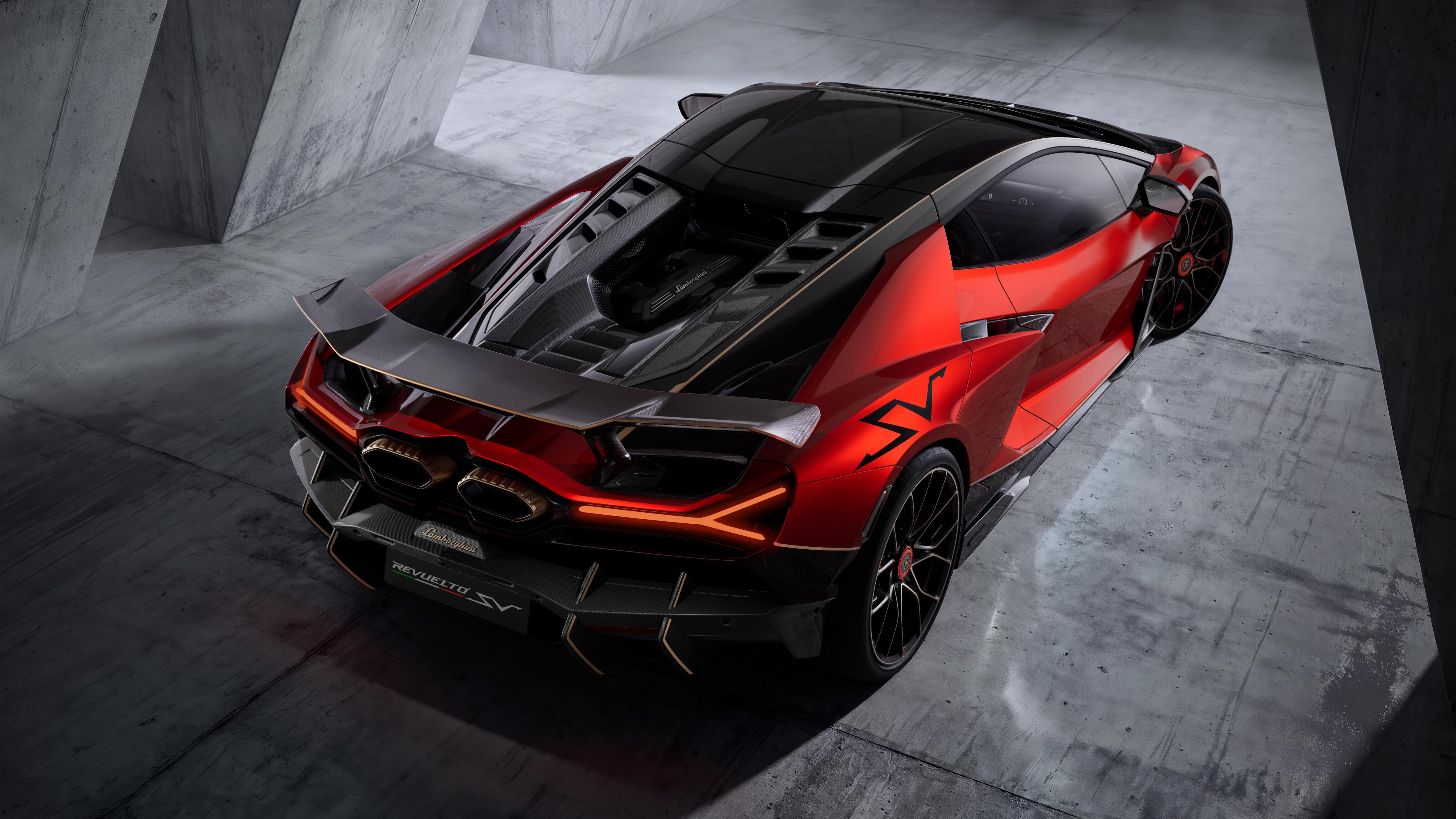Carro esportivo vermelho e preto, visto de cima e de trás, com design futurista e aerodinâmico, estacionado em um ambiente com paredes e chão de concreto cinza, iluminado por luzes indiretas