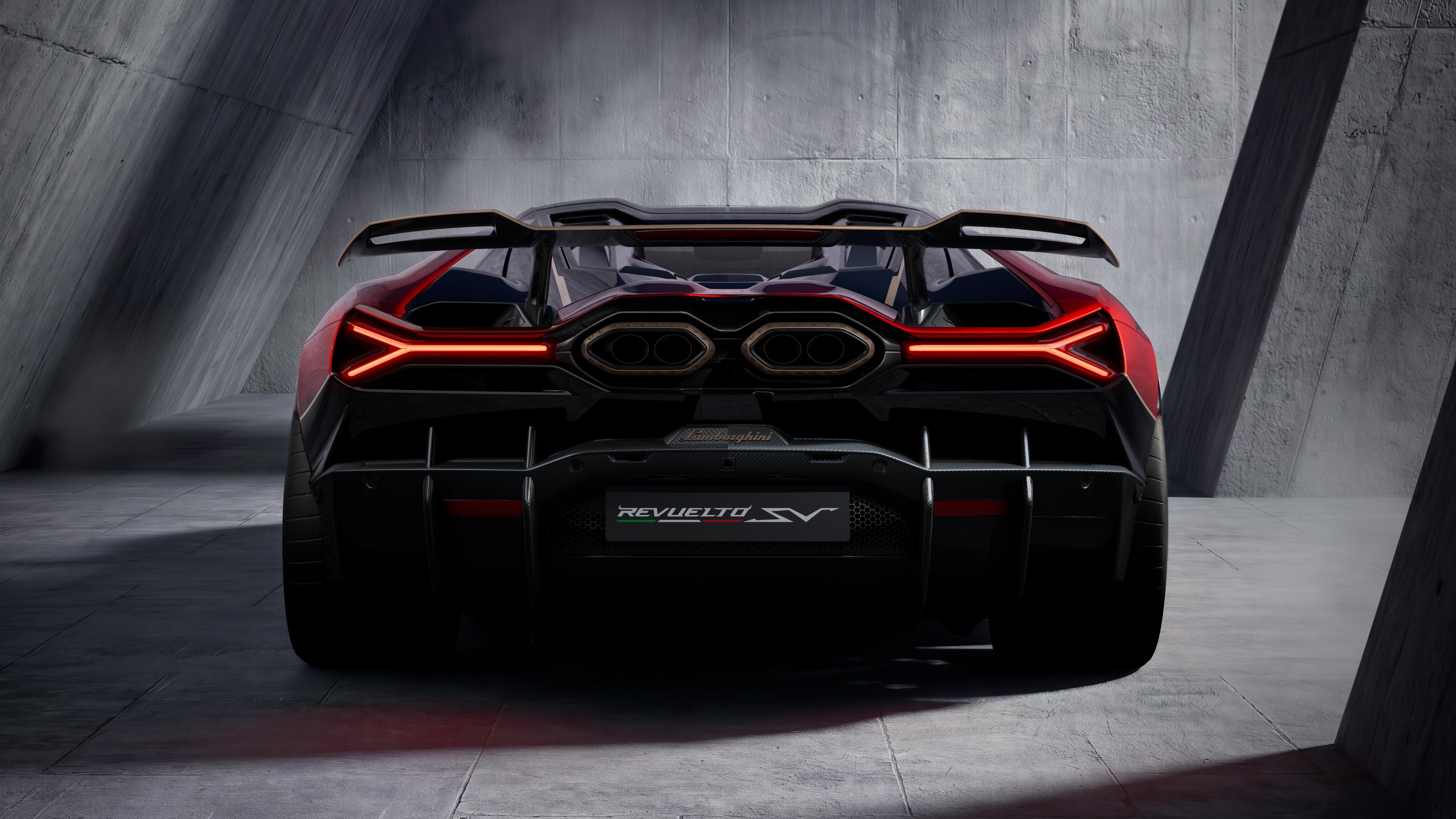 Traseira de um carro esportivo Lamborghini Revuelto SV vermelho e preto, com lanternas em formato de Y acesas em vermelho, escapamentos duplos e aerofólio. O veículo está em um ambiente escuro com paredes de concreto texturizado