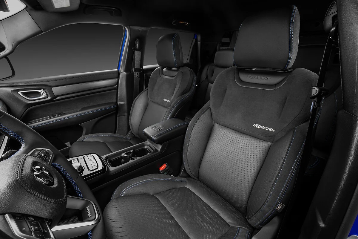 Interior de um carro com bancos esportivos em couro preto e suede, costuras azuis, volante multifuncional e console central com porta-copos
