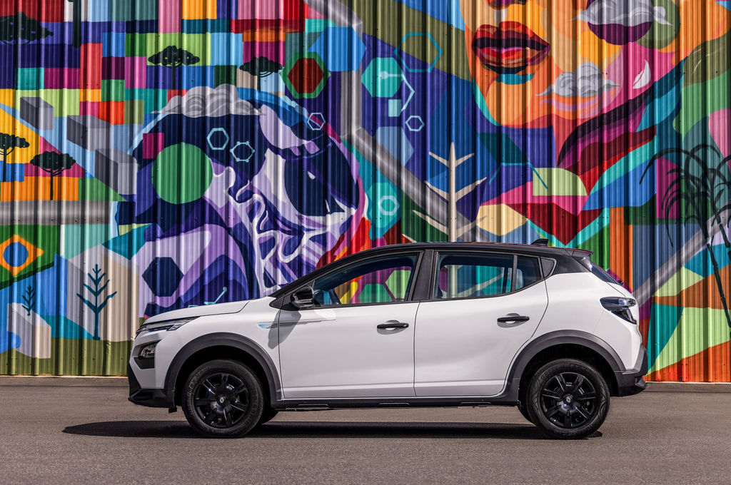 Carro branco com teto preto, modelo SUV compacto, estacionado de perfil em frente a um muro colorido com grafite abstrato e elementos da natureza