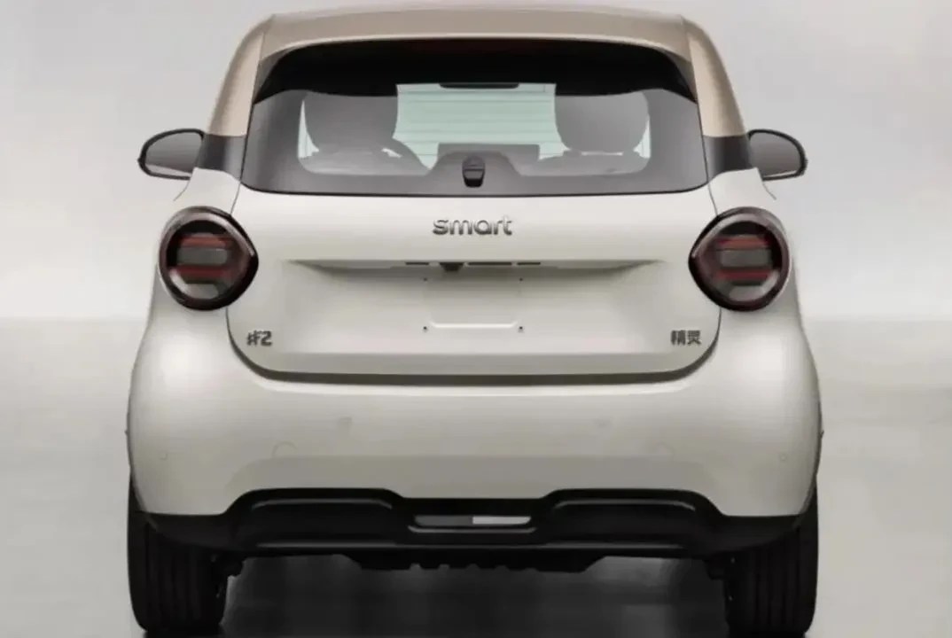 Traseira de um carro Smart branco com teto bege, visto de frente. As lanternas redondas escuras estão nas laterais, e o nome smart aparece no centro da tampa do porta-malas, acima do local da placa