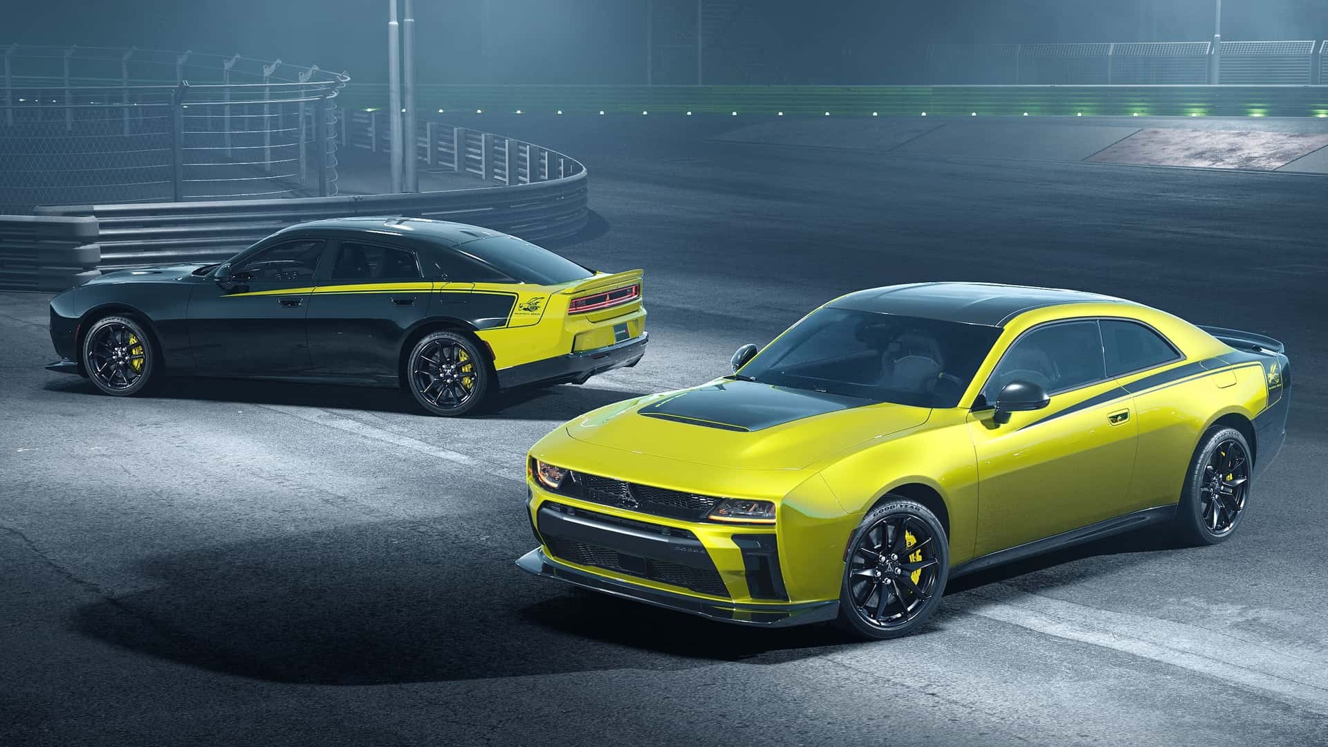 Dois carros esportivos, um cupê amarelo e preto em primeiro plano e um sedã preto e amarelo ao fundo, em uma pista de corrida noturna. O cupê tem faixas pretas e o sedã faixas amarelas, ambos com rodas escuras e pinças de freio amarelas. A pista é escura com iluminação suave e grades de proteção ao fundo