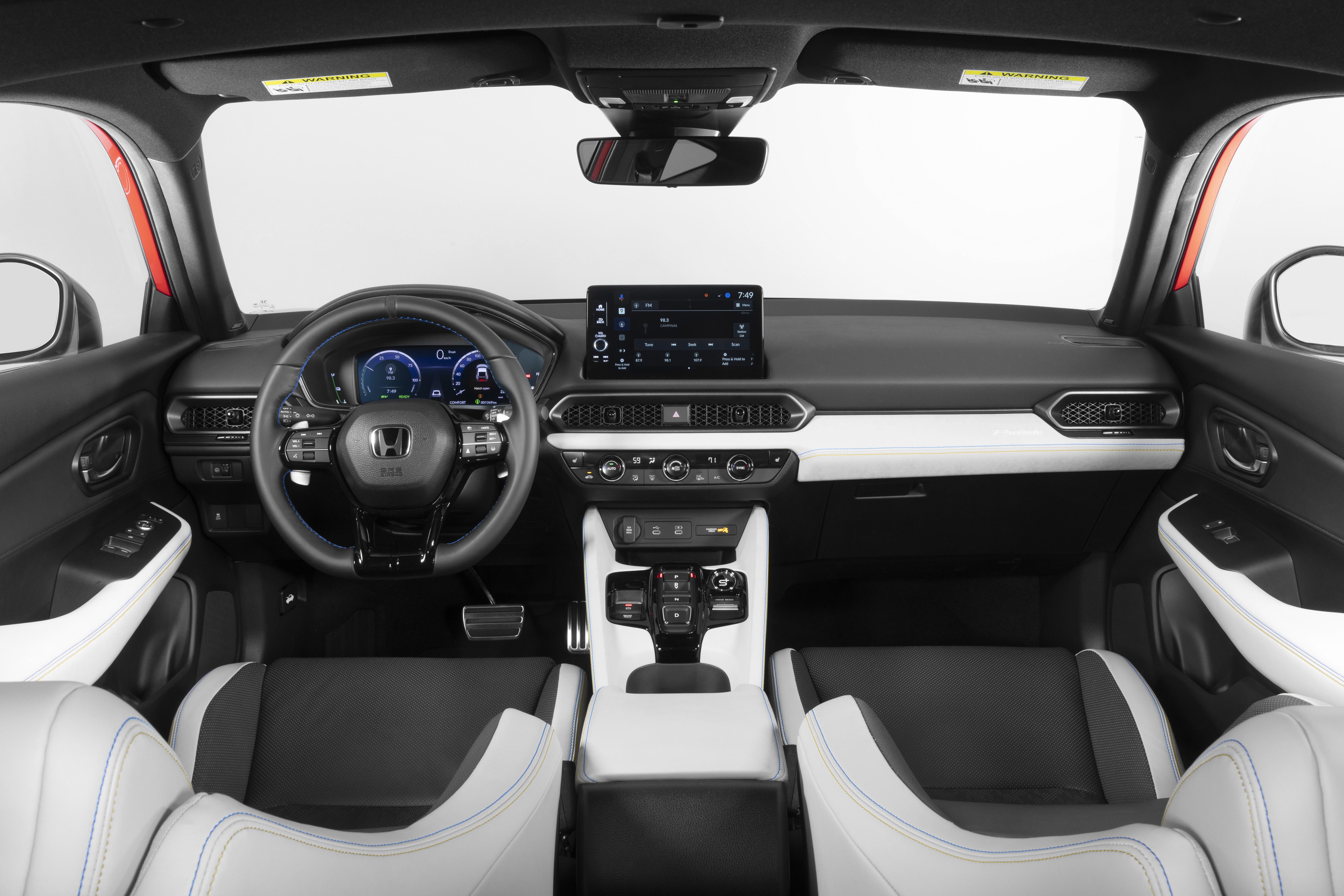 Interior de um carro moderno, com bancos dianteiros em couro branco e detalhes azuis, painel preto e branco, volante multifuncional com logo Honda, tela multimídia central e painel de instrumentos digital. O para-brisa e as janelas laterais mostram um fundo branco