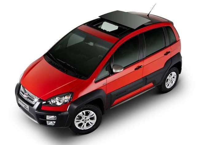 Carro Fiat Idea Adventure vermelho, com teto solar aberto, para-choques e molduras das rodas em plástico preto, visto de cima em ângulo diagonal sobre fundo branco