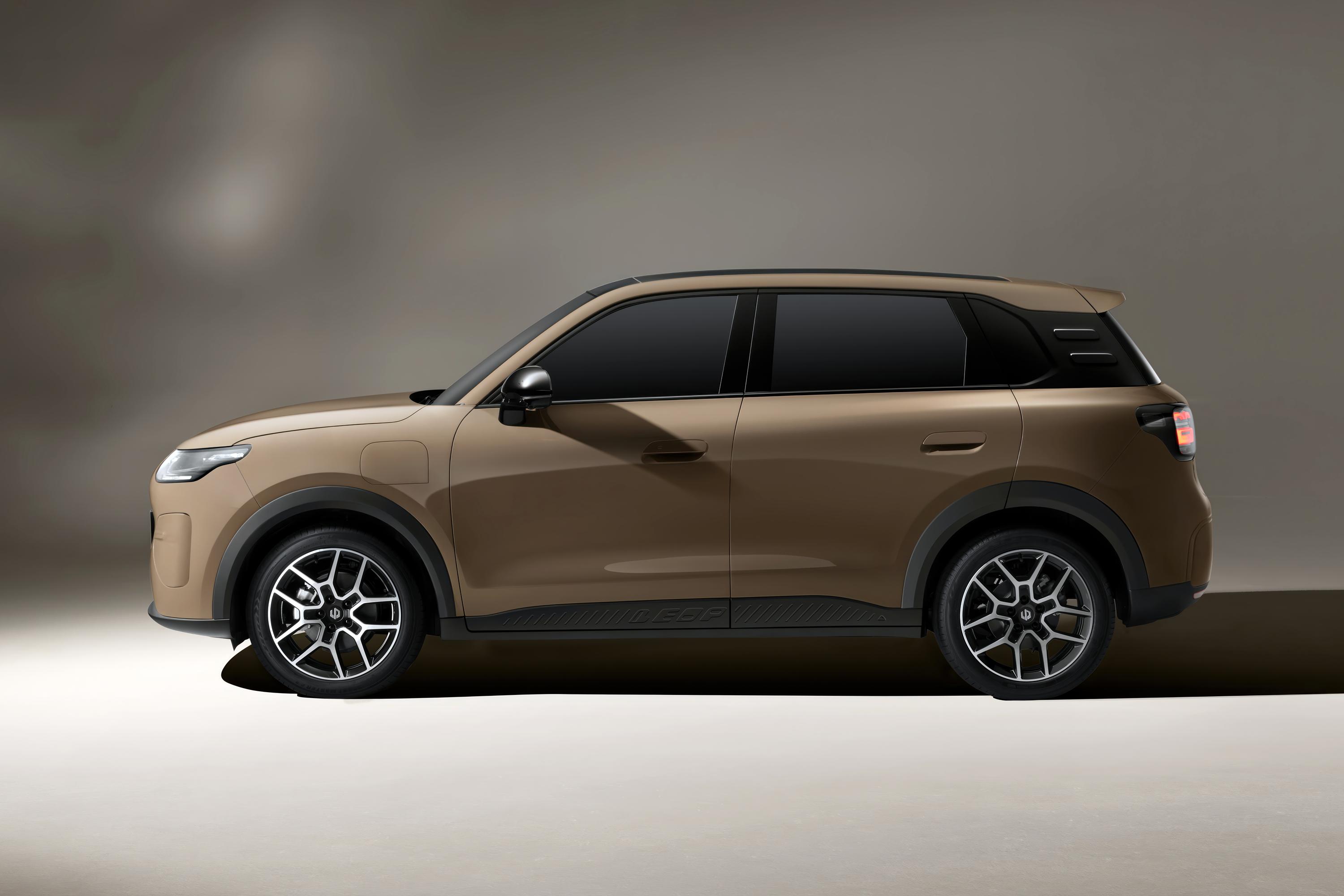 Carro SUV elétrico marrom claro, visto de perfil, com janelas escuras e rodas de liga leve em preto e prata, sobre fundo cinza