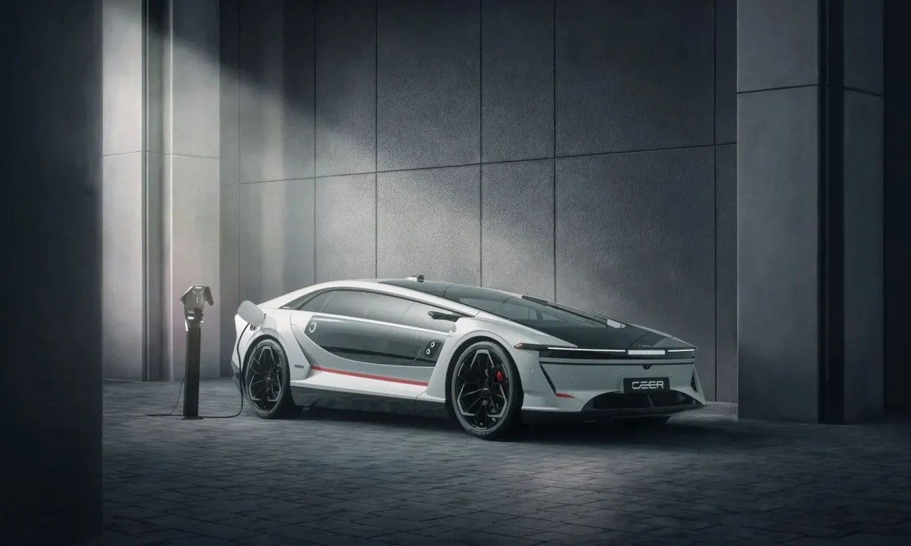 Carro elétrico futurista branco e cinza, com detalhes vermelhos, sendo carregado em uma estação de recarga em um ambiente escuro e moderno, com paredes cinzas e iluminação focada