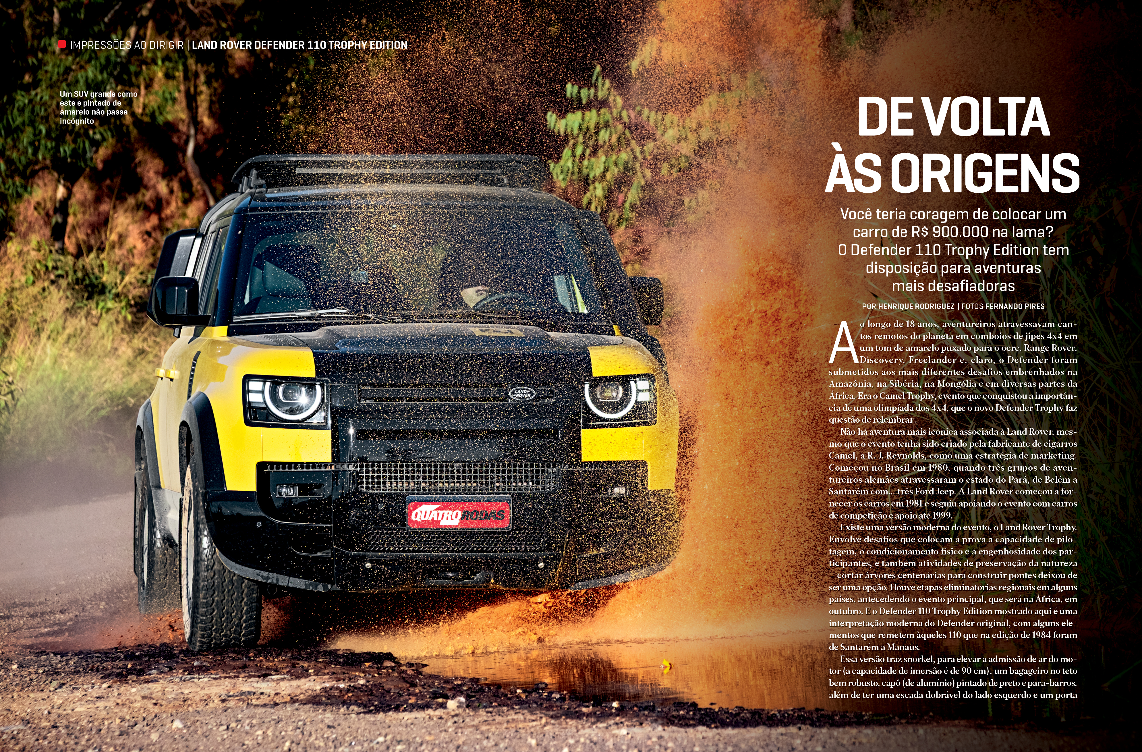 Um Land Rover Defender 110 Trophy Edition amarelo e preto, com teto preto, atravessa uma poça de lama, espirrando água e terra para cima e para os lados, em uma estrada de terra com vegetação ao fundo