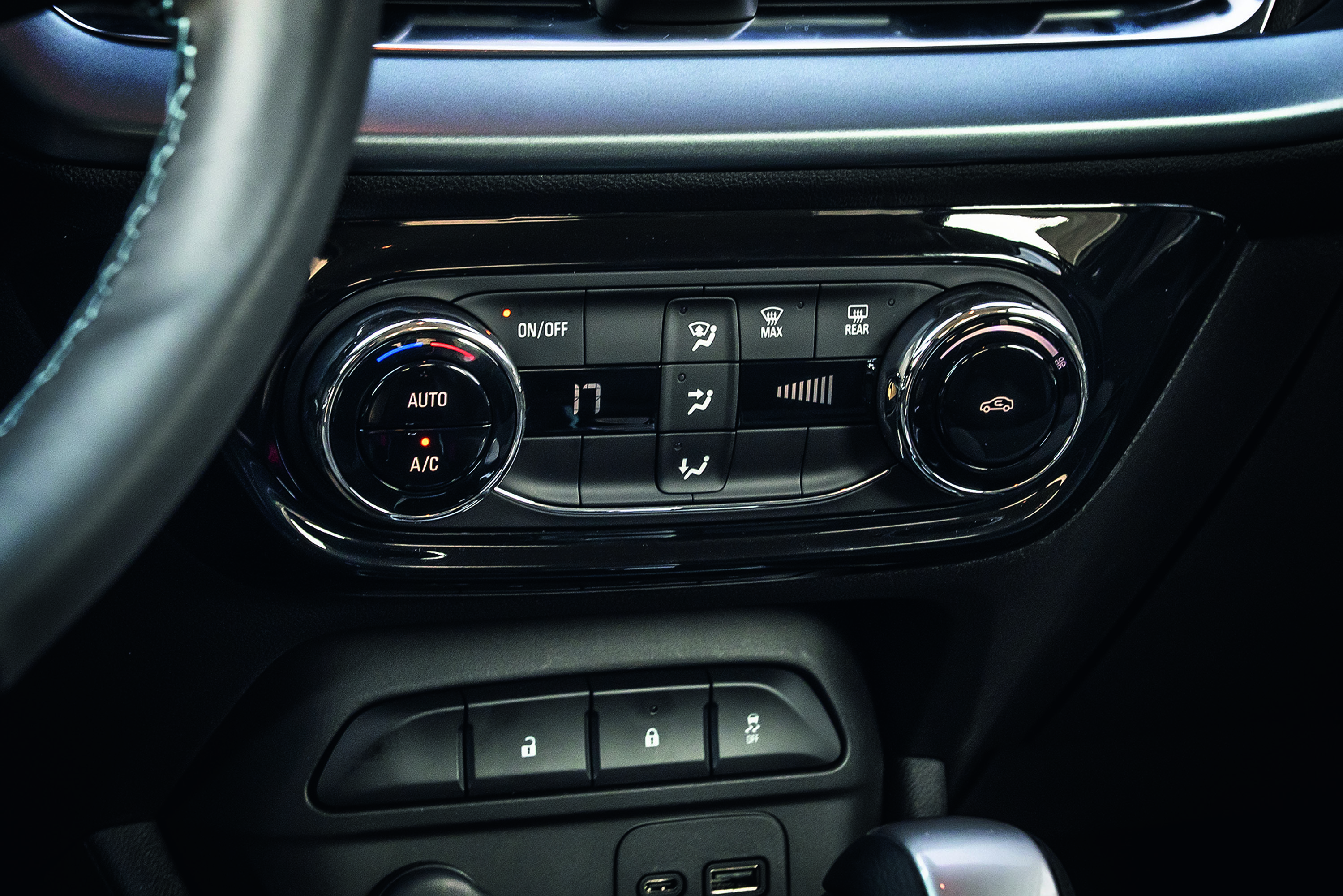 Painel de controle do ar-condicionado de um carro, com botões giratórios e de pressão, display digital mostrando 17, e entradas USB abaixo
