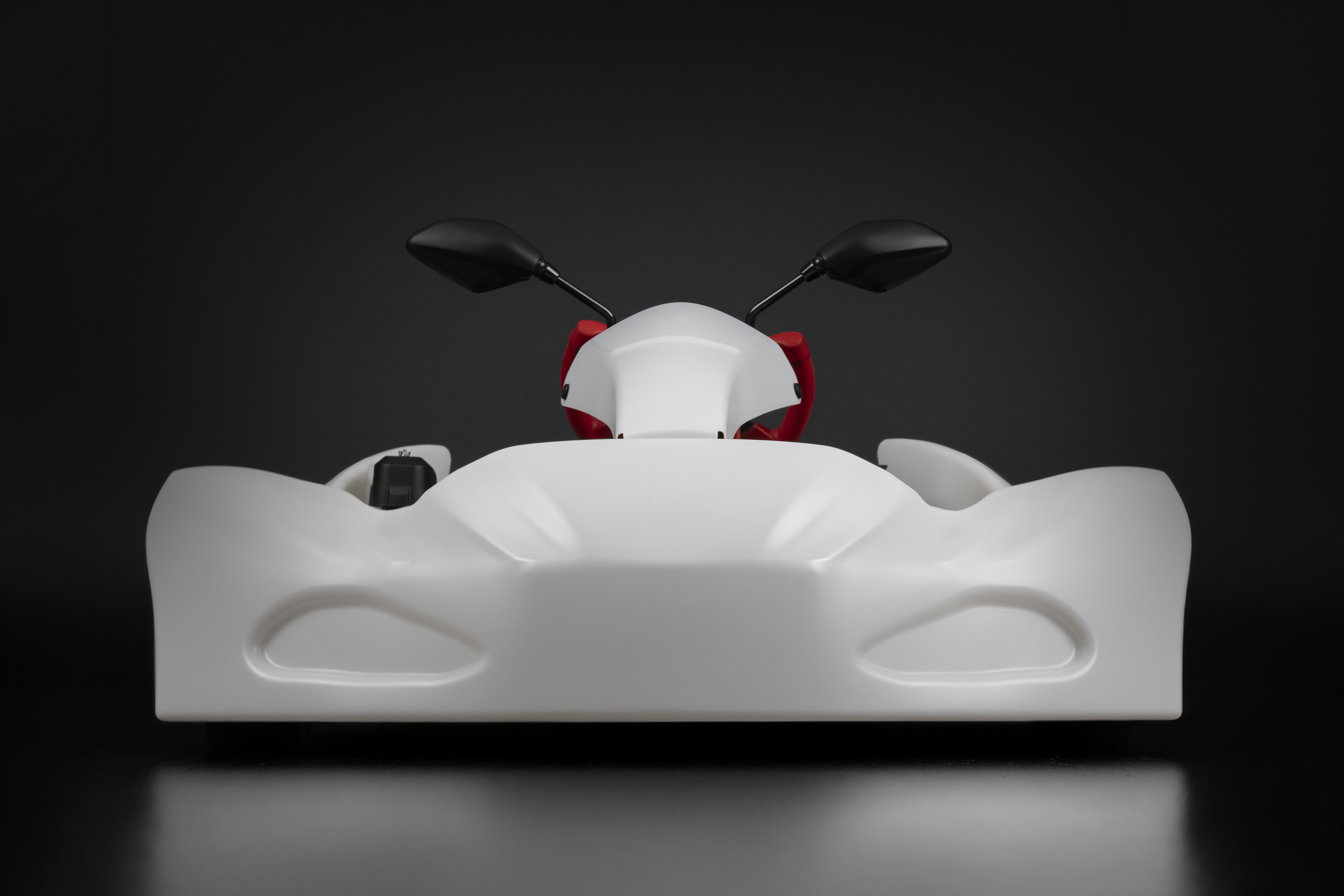 Frente de um kart branco com detalhes vermelhos e espelhos retrovisores pretos, em fundo escuro