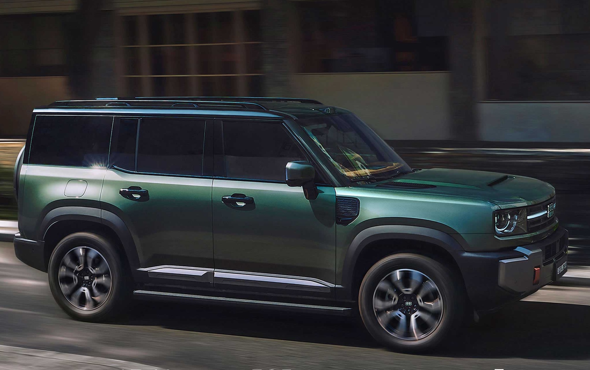 SUV verde escuro com teto preto e rack de teto, em movimento na rua, com prédios desfocados ao fundo