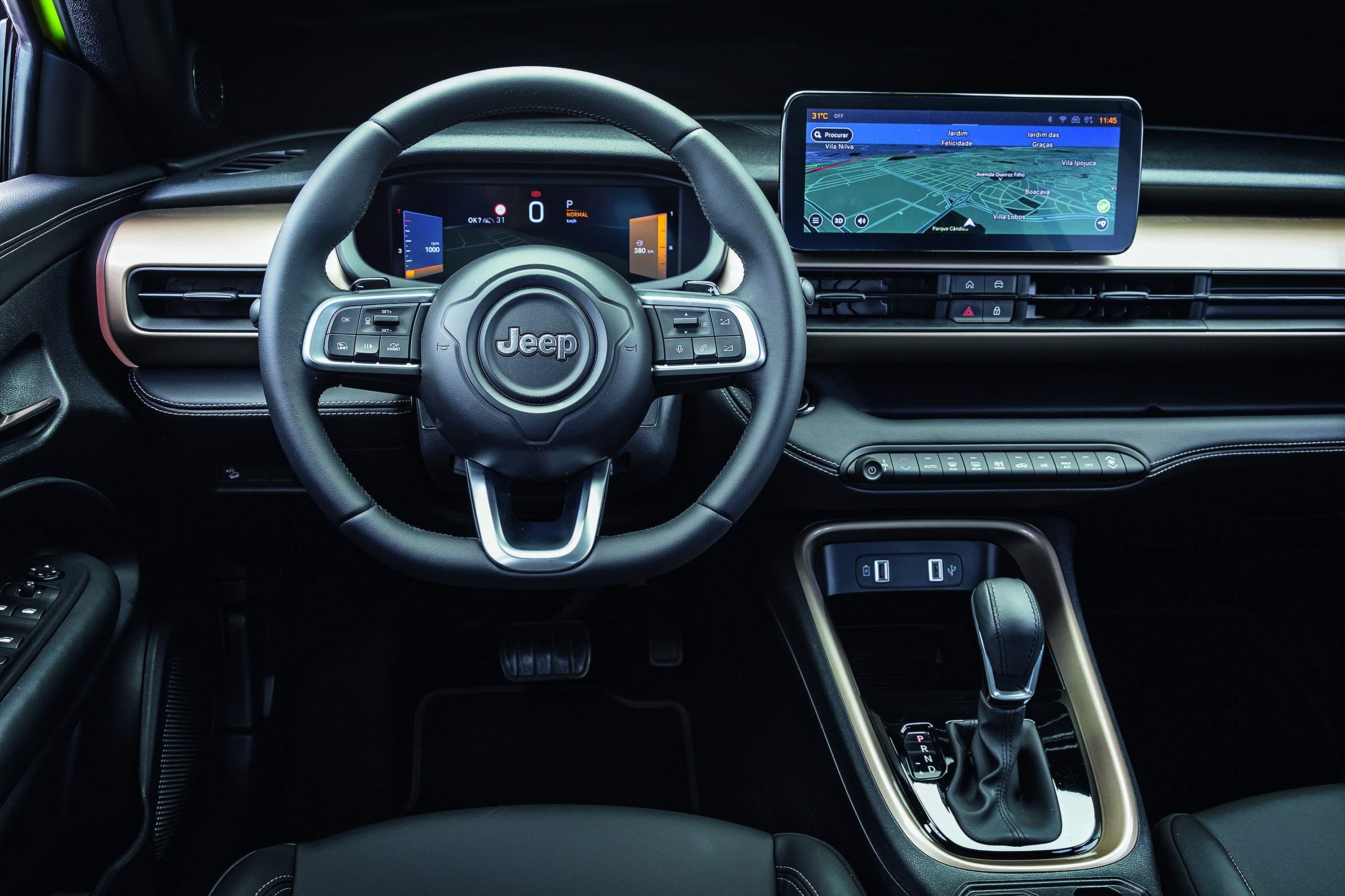 Interior de um carro moderno, com volante preto da marca Jeep, painel digital exibindo velocímetro e tela multimídia com mapa de navegação. O console central possui câmbio automático e entradas USB.