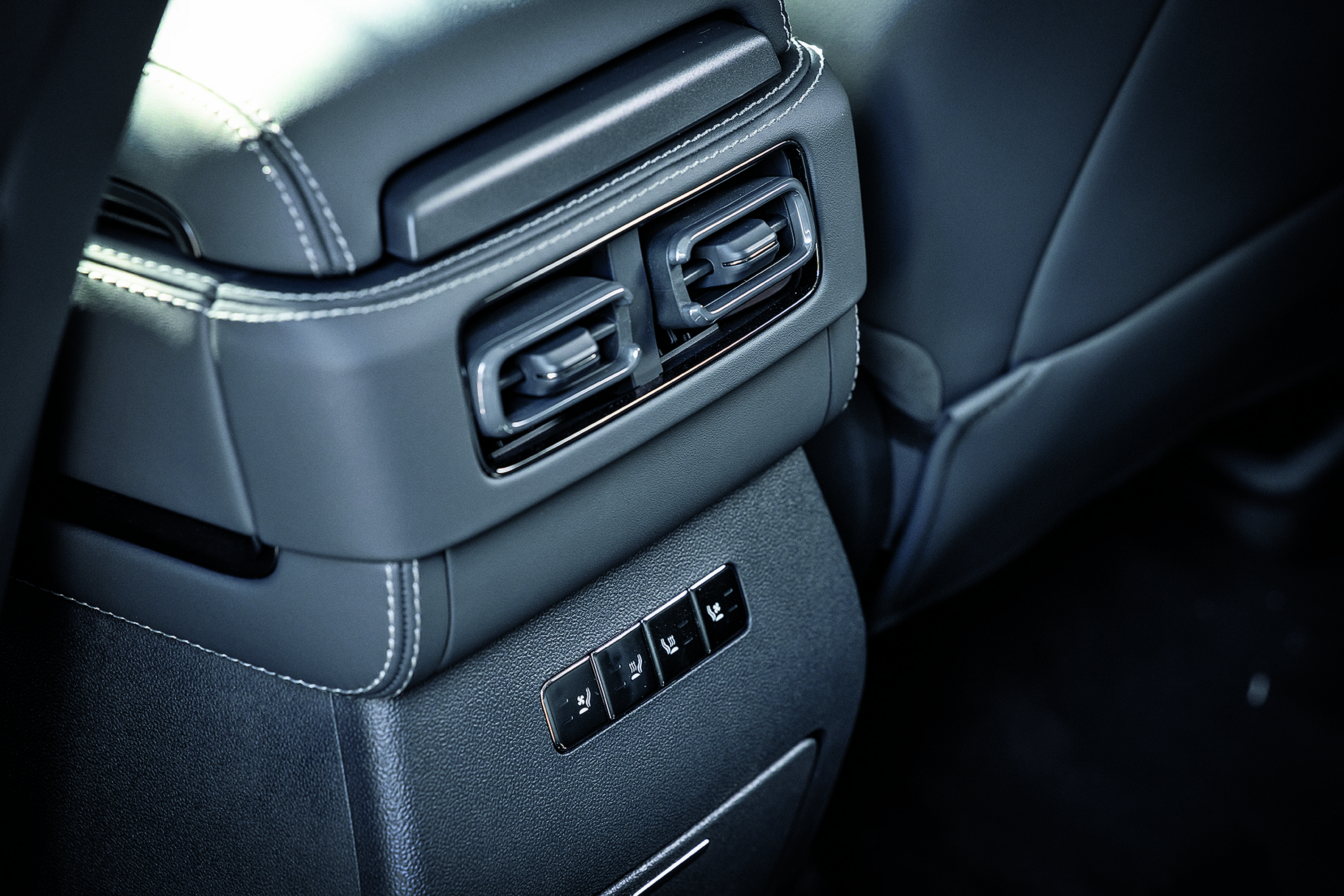 Interior de carro com saídas de ar e botões de controle de assento no console traseiro, estofamento cinza escuro com costura branca