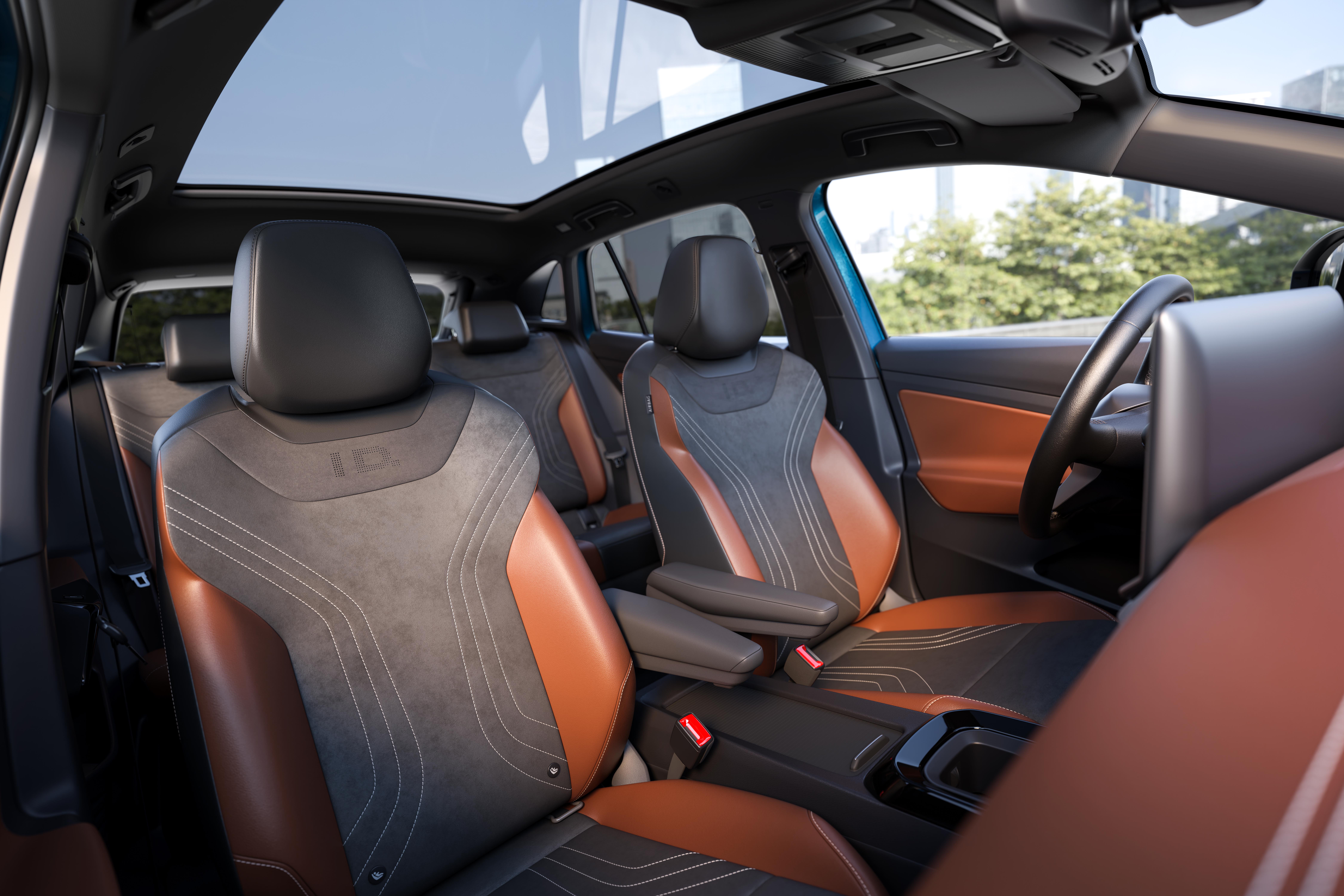 Interior de carro moderno com bancos de couro marrom e tecido cinza escuro, costuras brancas e logotipo ID nos encostos. Teto solar panorâmico de vidro, volante visível à direita e árvores ao fundo