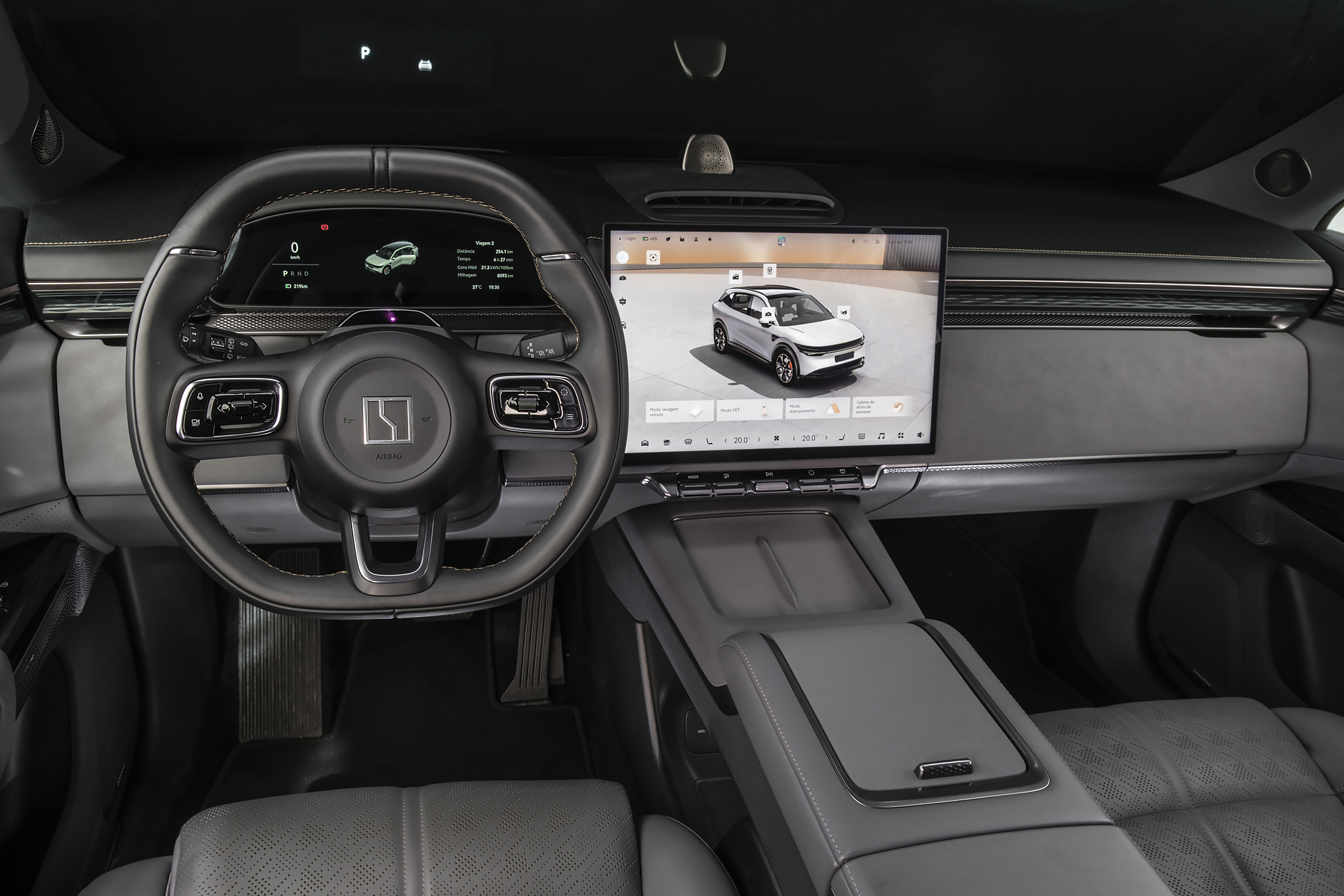 Interior de um carro moderno com volante preto e painel digital. Uma tela central exibe um SUV branco em 3D, com opções de personalização. O console central é cinza escuro, com porta-objetos e assentos de couro perfurado. O ambiente é sofisticado e tecnológico