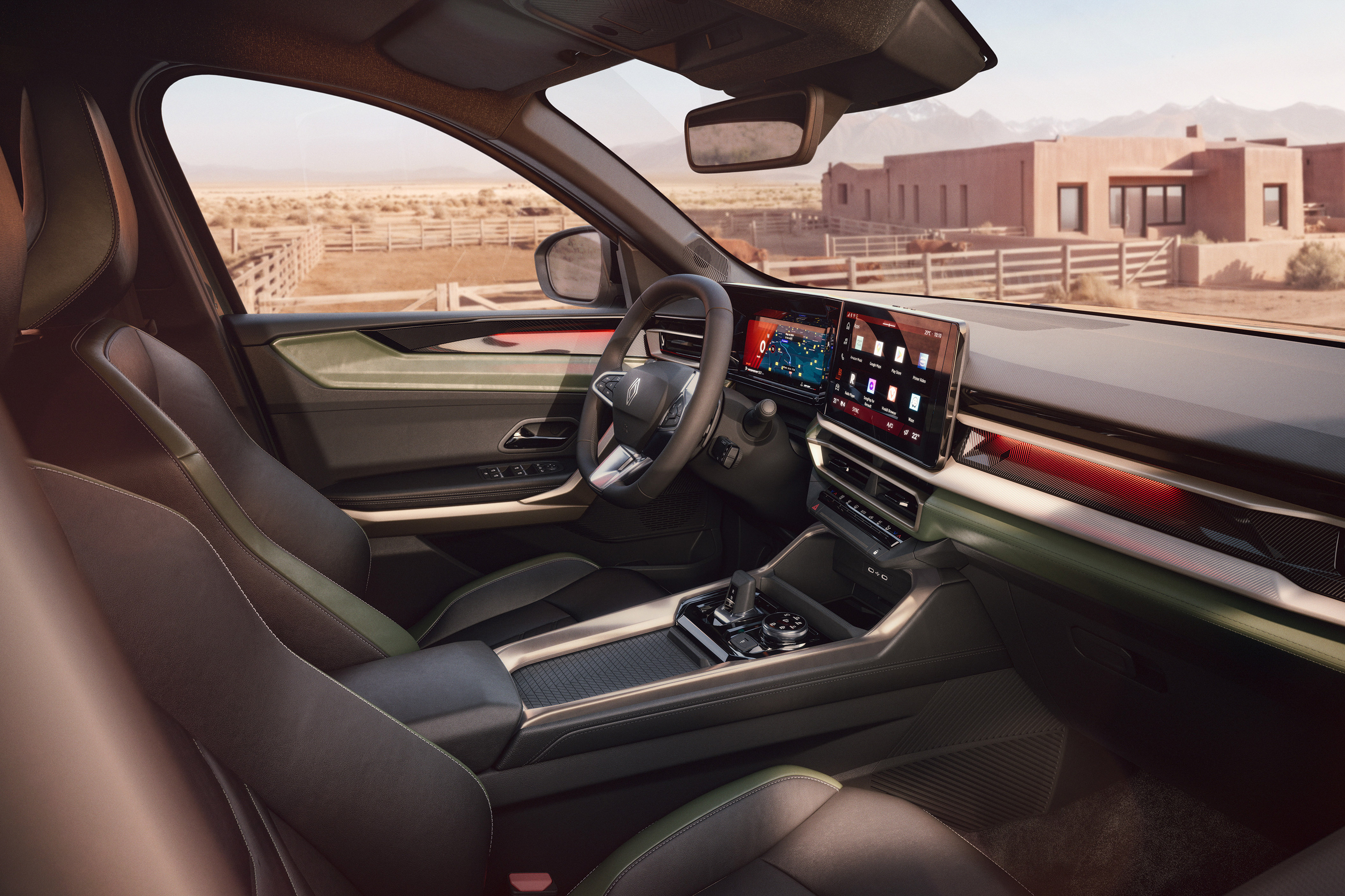Interior de um carro moderno com bancos de couro escuro e detalhes em verde-oliva. O painel possui duas telas digitais grandes, uma para o motorista e outra central com aplicativos. Ao fundo, uma paisagem desértica com montanhas, uma cerca de madeira e uma casa de estilo adobe