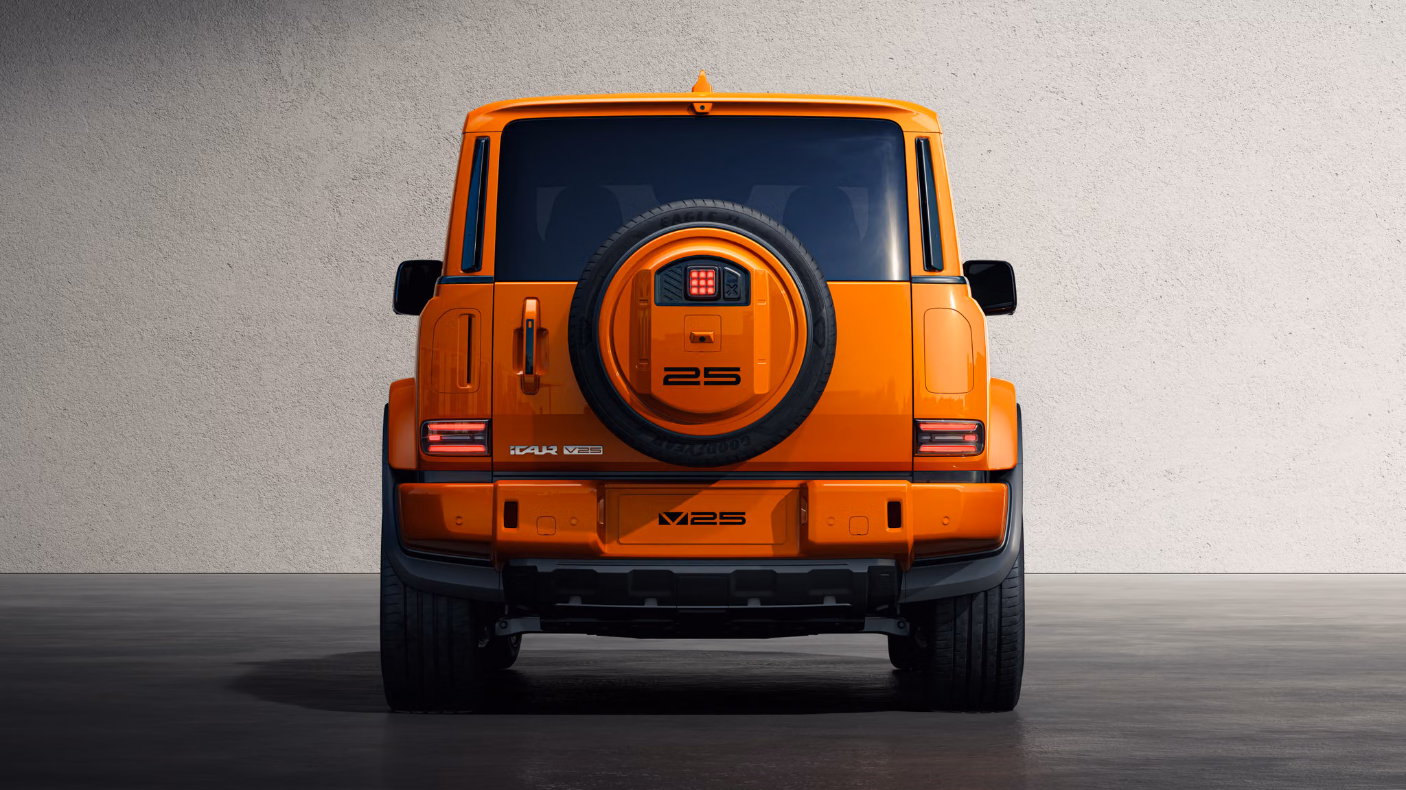 SUV laranja com design robusto, faróis redondos acesos e grade frontal retangular, estacionado em um estúdio com piso reflexivo e parede escura