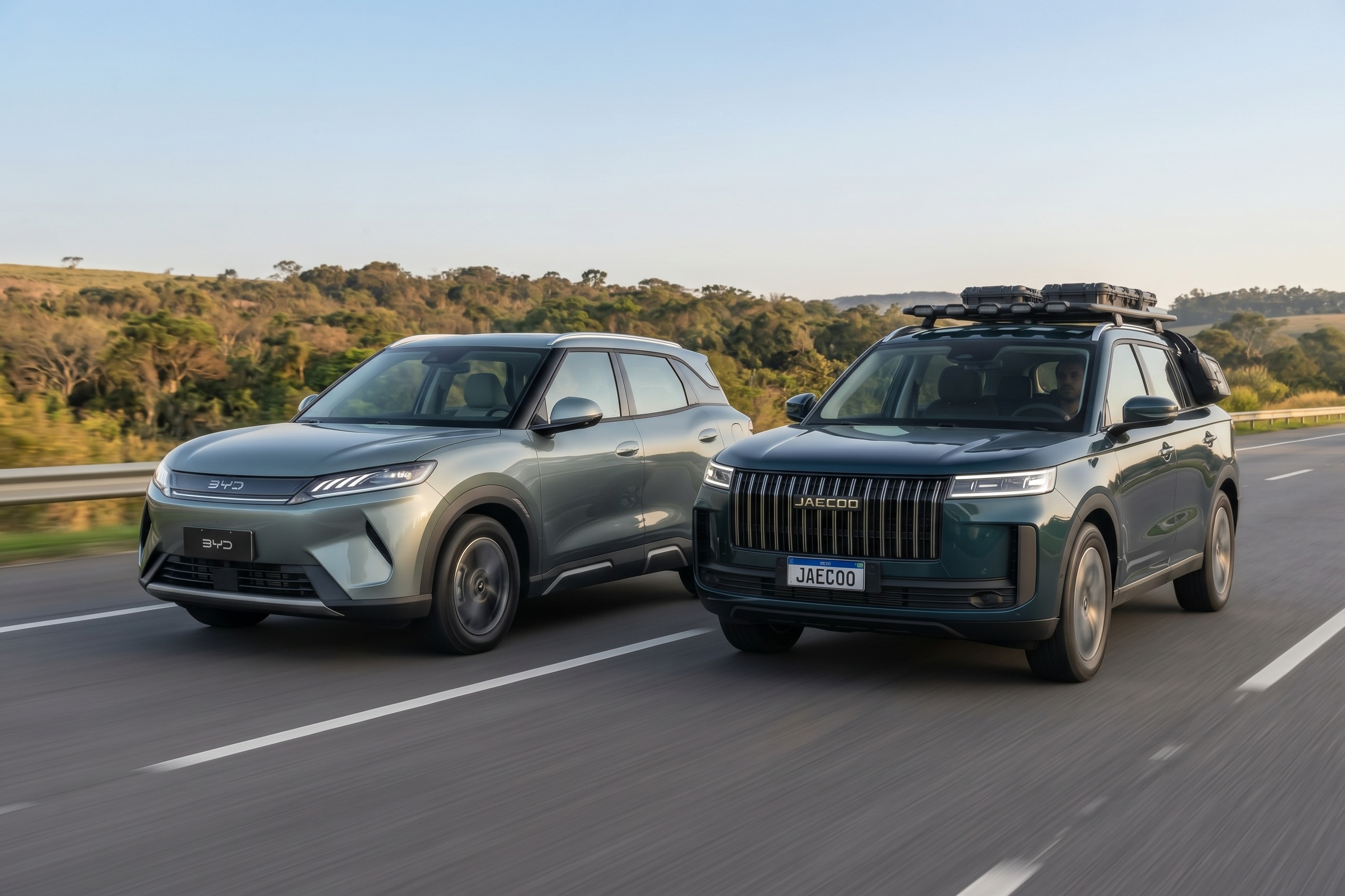 Dois SUVs, um BYD Song Pro cinza-esverdeado e um Jaecoo 7 verde-escuro com bagageiro de teto, trafegam lado a lado em uma rodovia com vegetação ao fundo