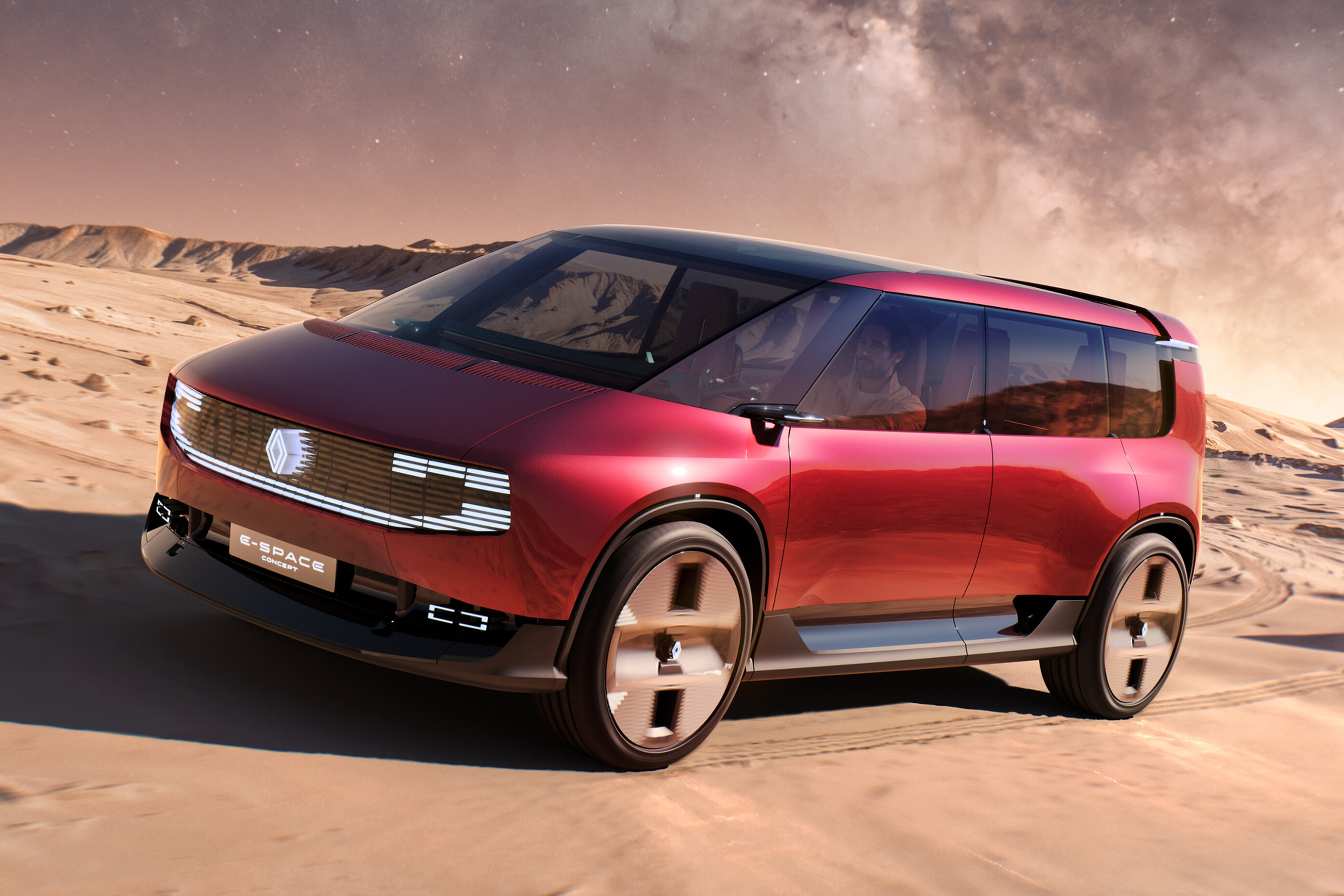 Minivan conceito Renault E-Space vermelha escura, com teto preto e rodas de design futurista, estacionada em uma paisagem desértica com dunas e céu alaranjado estrelado