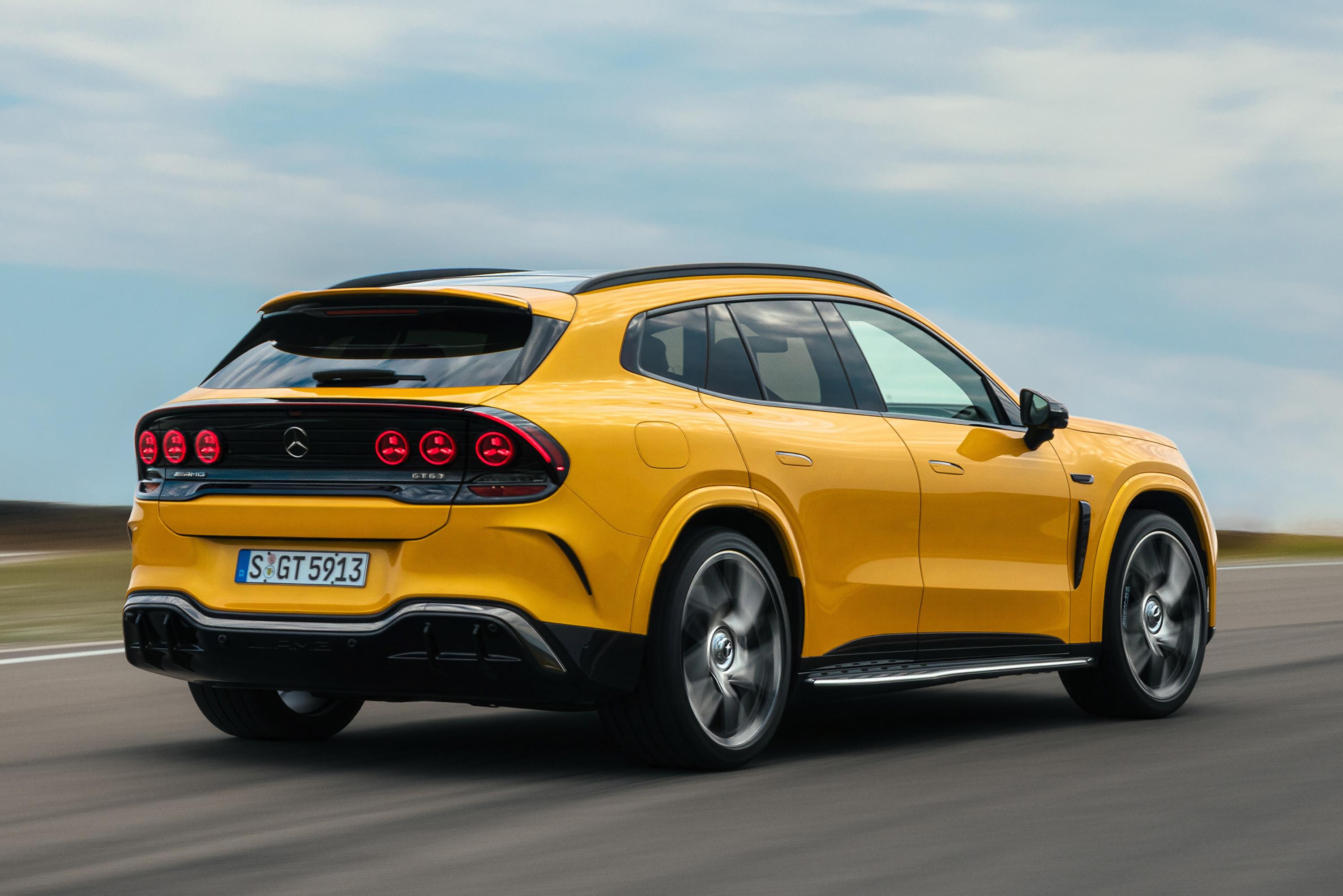 SUV amarelo brilhante em movimento, visto de trás e lateralmente, com rodas girando rapidamente. O carro tem teto preto, lanternas traseiras redondas e placa S GT 5913. O fundo é um céu azul claro com nuvens esparsas e uma estrada cinza