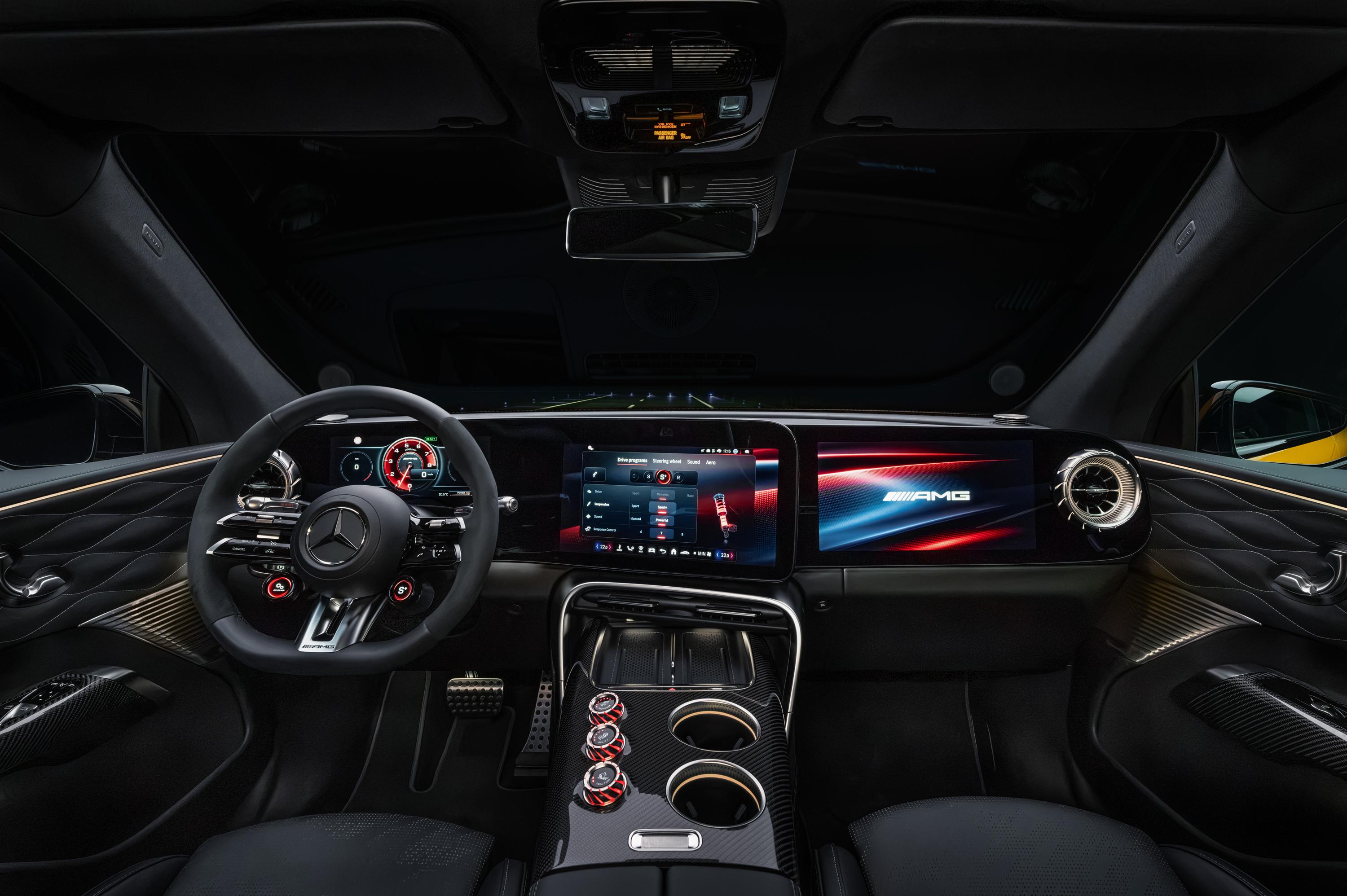 Interior de um carro Mercedes-Benz AMG com volante esportivo, painel digital com três telas exibindo informações do veículo e o logotipo AMG, e console central com porta-copos e botões de controle vermelhos. O estofamento das portas é preto com detalhes em costura diamante
