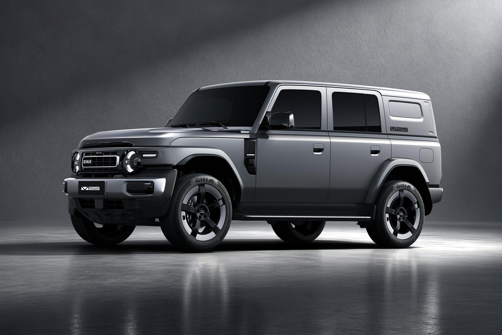 Um SUV cinza escuro, com design robusto e moderno, estacionado em um estúdio com fundo cinza e iluminação focada, destacando suas linhas retas e rodas pretas com detalhes brancos